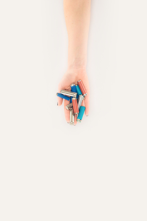cropped shot of woman holding batteries isolated on white