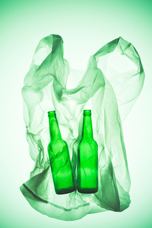 crumpled plastic bag with glass bottles under green toned light