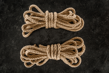 top view of arrangement of tied brown marine ropes on dark concrete surface