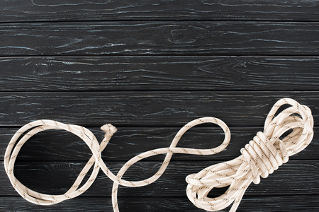 top view of tied white marine rope on dark wooden tabletopの写真素材