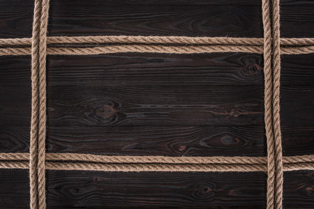 top view of arrangement of brown nautical ropes on dark wooden tabletopの写真素材