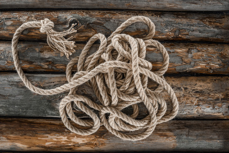 top view of nautical rope with knot on grunge wooden surface