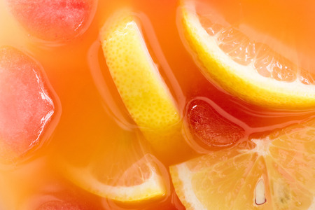 close up view of fresh cocktail with ice cubes and lemon pieces backgroundの写真素材