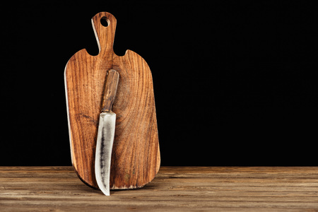 closeup view of knife and wooden cutting board on black background の写真素材