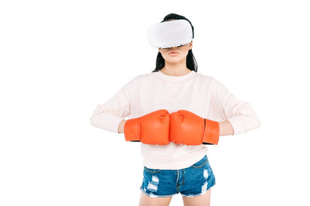 attractive young asian woman in virtual reality headset and boxing gloves posing isolated on white