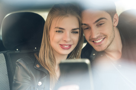 portrait of happy couple in love taking selfie while sitting in car