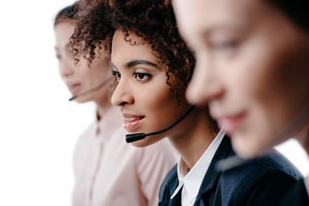 multiethnic female operators working with headset, isolated on white の写真素材