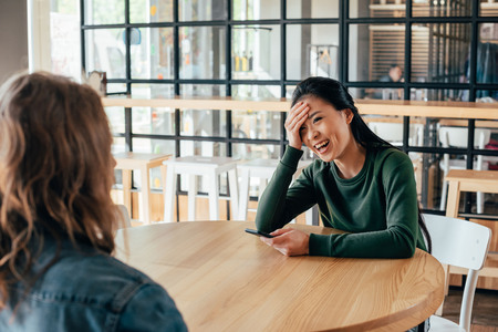Portrait of young asian woman spending time with friend in cafeの写真素材