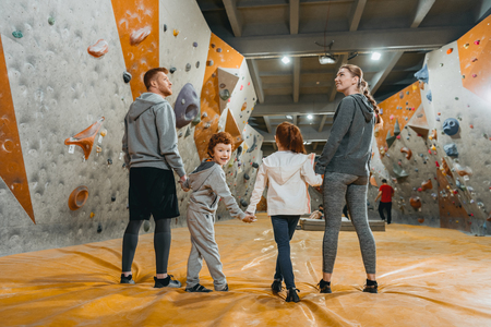 Full-length shot of family with kids holding hands and standing in a row at gymの写真素材