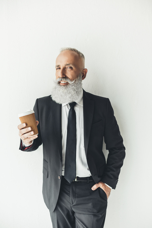 senior businessman with paper cup of coffee on light backgroundの写真素材