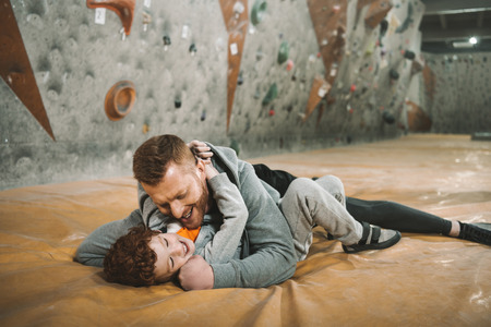Full-length shot of dad knocking down son on mat at gymの写真素材