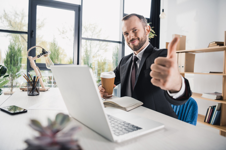 handsome young businessman showing thumb up の写真素材