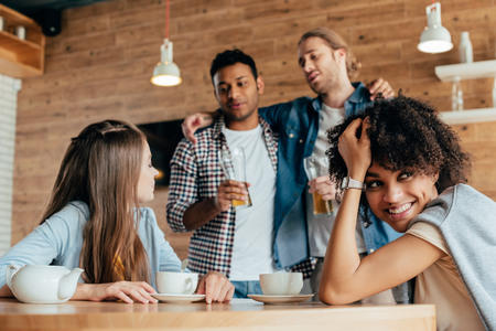two drunk men are wary of young women sitting in cafeの写真素材