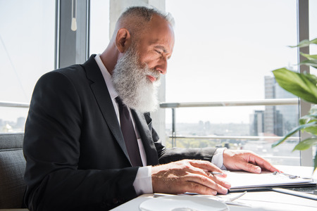 thoughtful mature businessman with business contract to signの写真素材