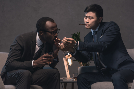 successful multiethic businessmen smoking cigarsの写真素材