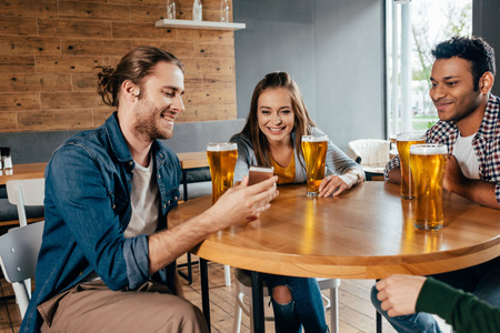 Happy young friends spending good time together in cafeの写真素材