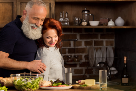 portrait of smiling senior couple looking at ingredients for dinner on table in kitchenの写真素材
