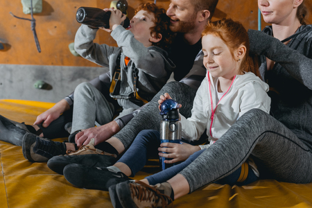 Family with children sitting on a mat at gym with climbing walls in the backgroundの写真素材