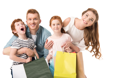 happy young family with two kids holding shopping bags isolated on whiteの写真素材