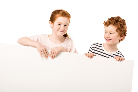 adorable smiling red haired kids holding blank banner isolated on whiteの写真素材