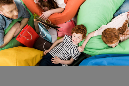 top view of happy young family with shopping bags resting on bean bag chairs の写真素材