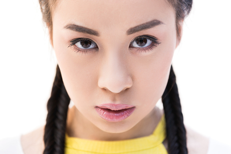 close-up portrait of serious asian girl looking at camera isolated on white の写真素材