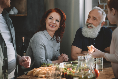 partial view of cheerful senior couple with family in kitchen at homeの写真素材