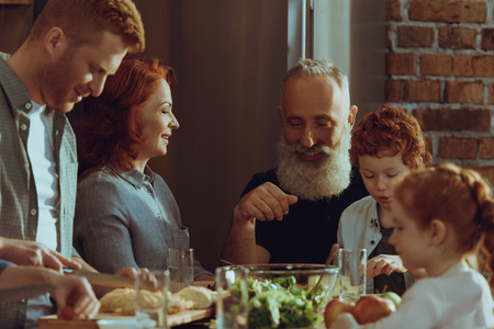 happy multigeneration family cooking dinner together at home