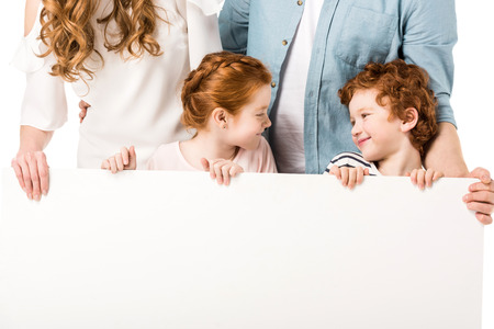 cropped shot of young family with two kids holding blank banner isolated on whiteの写真素材