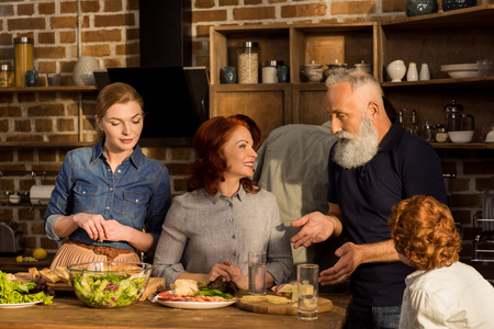portrait of happy multigeneration family having conversation in kitchen at home