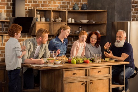 multigeneration family cooking dinner together in kitchen at home