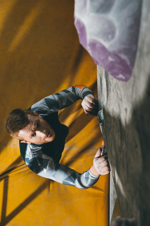 High angle shot of young man in sport attire, prepared to climb a wall with grips at gymの写真素材