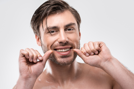 handsome man using dental floss, isolated on whiteの写真素材