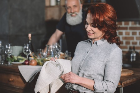 selective focus of smiling woman cleaning wine glass at homeの写真素材