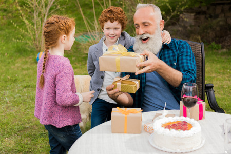little boy and girl greeting happy grandfather at birthday celebrationの写真素材