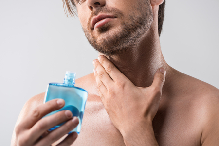 cropped view of handsome man using shaving lotion, isolated on whiteの写真素材