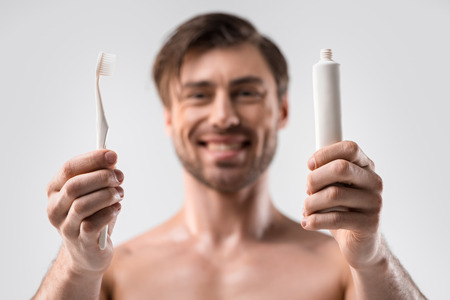 selective focus of man holding toothbrush and toothpaste, isolated on whiteの写真素材