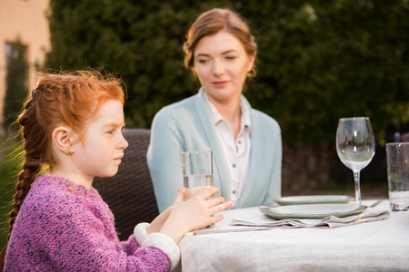 selective focus of mother and little daughter having dinner togetherの写真素材