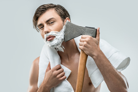 handsome man in foam shaving with ax, isolated on whiteの写真素材