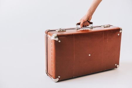 cropped shot of female hand holding retro suitcase isolated on grey