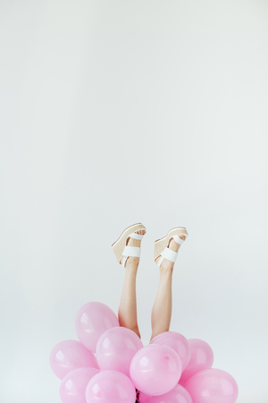 partial view of female legs and bunch of balloons isolated on greyの写真素材