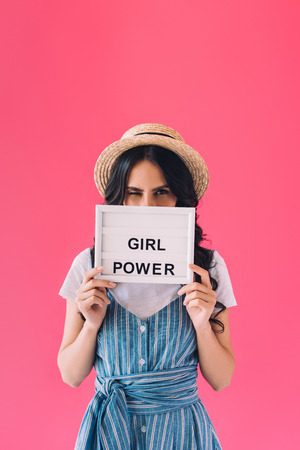 obscured view of woman holding board with girl power lettering isolated on pinkの写真素材
