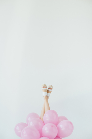 partial view of female legs and bunch of balloons isolated on greyの写真素材