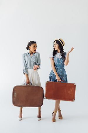 multiethnic women in retro clothing with luggage in hands isolated on greyの写真素材