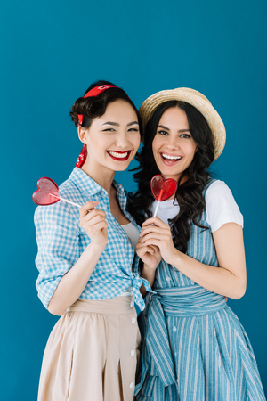 portrait of multicultural women with lollipops isolated on blueの写真素材