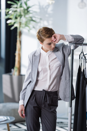 beautiful young fashion designer leaning on bar with dressesの写真素材