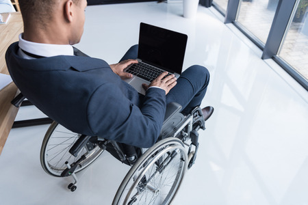 cropped shot of disabled african american businessman typing on laptop in officeの写真素材