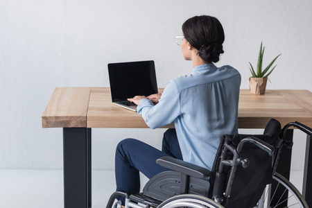 back view of disabled african american businesswoman working on laptop at workplace