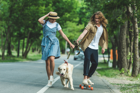 happy young couple riding on board and walking with dogの写真素材