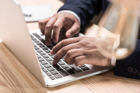 close up view of businessman typing on laptop at tableの写真素材